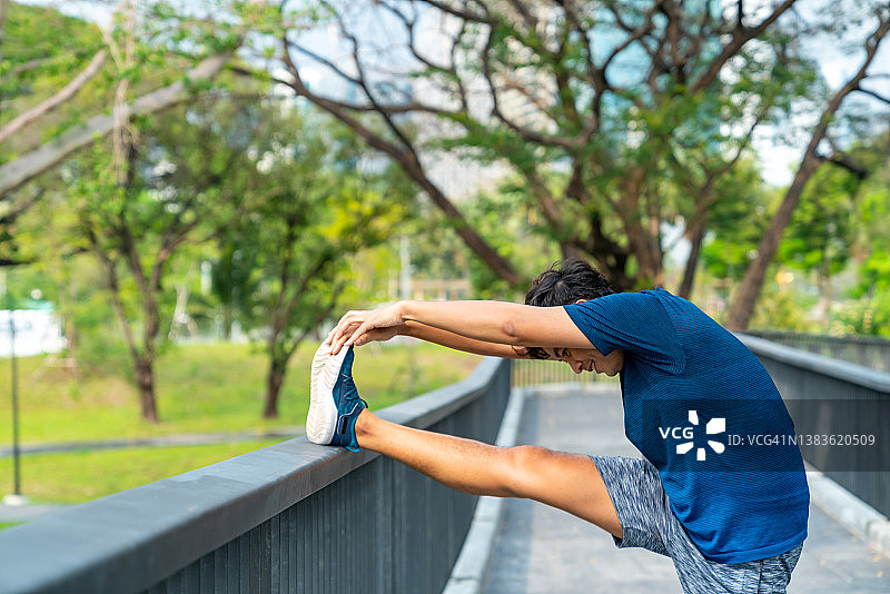 亚洲男子伸展身体，而慢跑运动在公园早上。图片素材