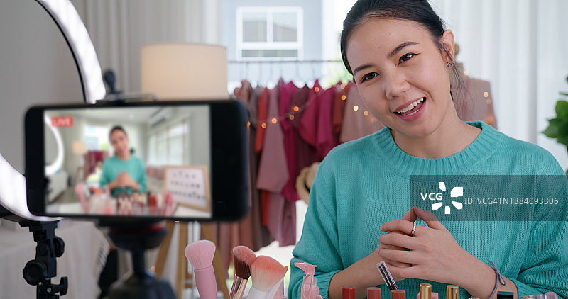 亚洲女性微博网红在家庭工作室录制直播视频。在媒体中快乐的谈笑说笑的建议回顾爱好。视频博主自拍拍摄享受工作展示微笑教像分享应用。图片素材