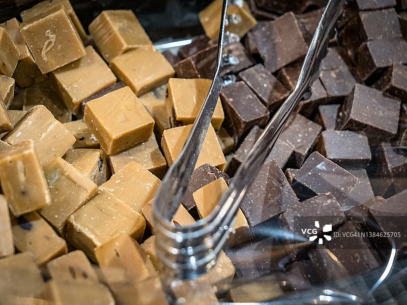 豪华美味的牛奶和白巧克力软糖糖果方块的宏观特写，自助式的勺子填满了整个框架。甜食和糖果图片素材