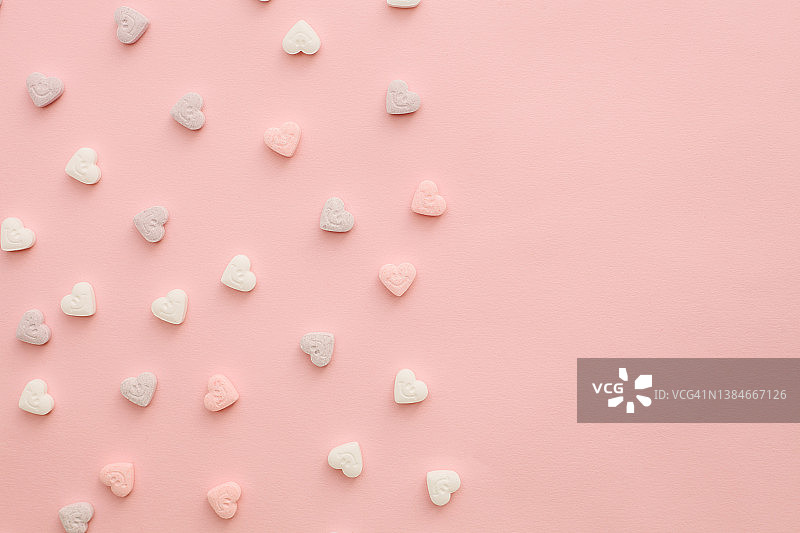 多色的粉红色和白色糖果在心的形状在柔和的粉红色背景图片素材