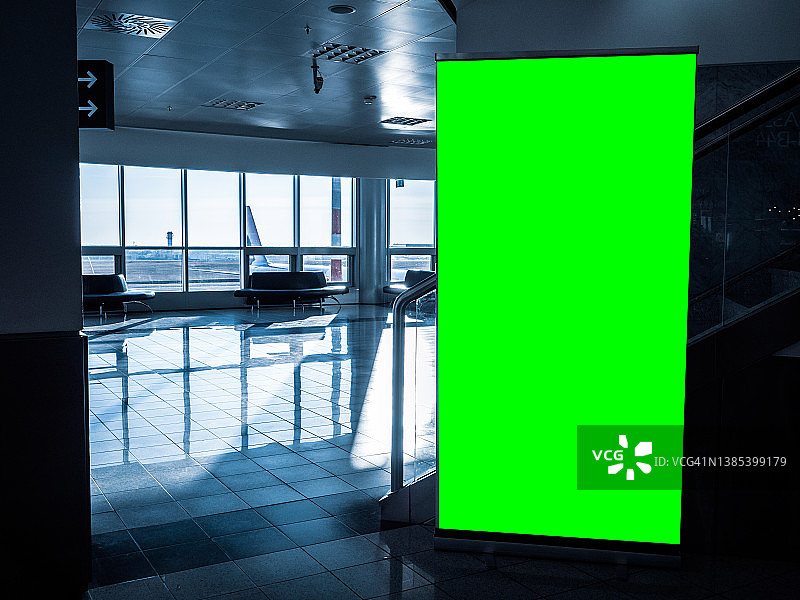在机场候机大厅设置的大型绿色屏幕空白空白营销广告牌。ChromaKey与复制空间完美的度假，假期和旅游营销。图片素材