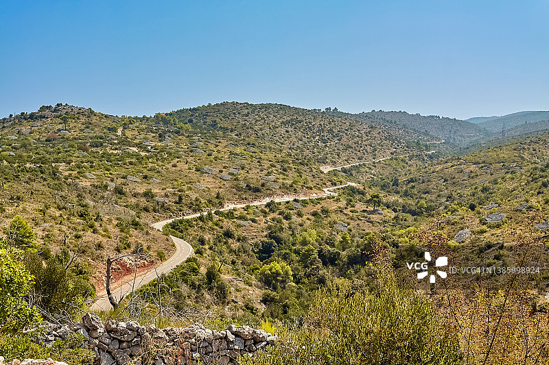 克罗地亚布拉克岛Lozisca村附近，一条狭窄的柏油路蜿蜒在山丘上。图片素材