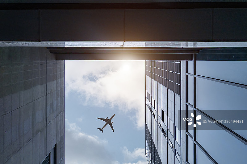 飞机在商业区的现代建筑上空飞行图片素材