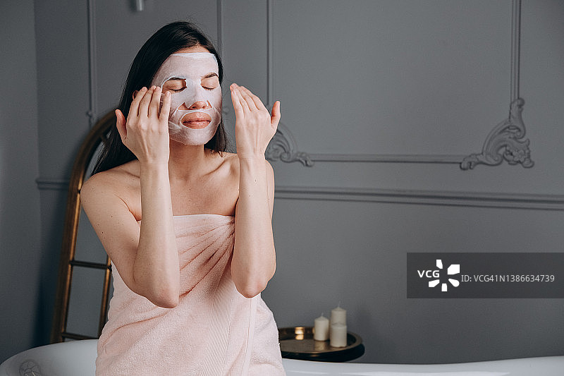 美丽的女人用保湿面膜敷在脸上，在家洁面和抗衰老治疗图片素材