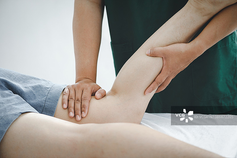 现代临床治疗大腿受伤疼痛的咨询治疗师。治疗久坐引起的大腿疼痛物理康复的概念。图片素材