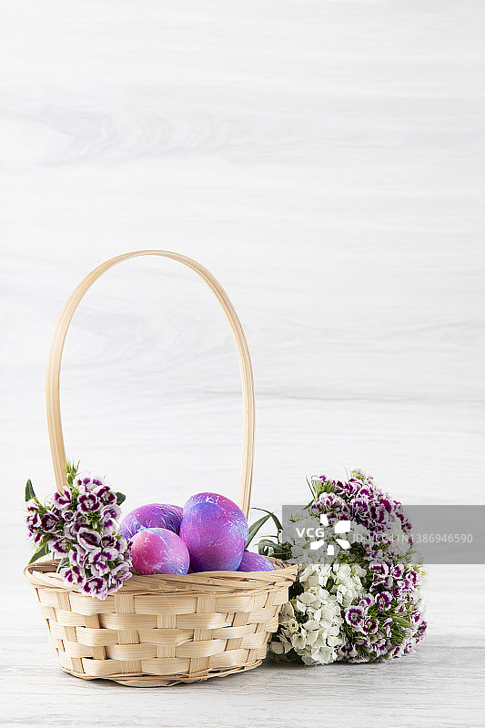 复活节彩蛋在一个篮子上的白色木制背景图片素材
