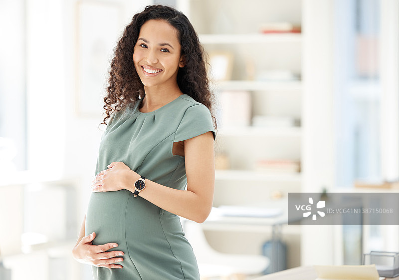 一个怀孕的女商人站在办公室的肖像图片素材