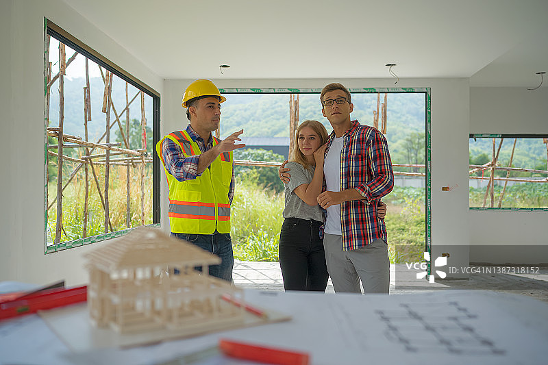 幸福的夫妻和建筑承包商在工地上谈论住房计划。图片素材
