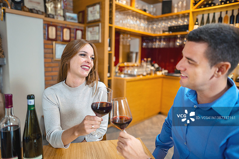 年轻夫妇坐在酒庄餐厅用葡萄酒举杯图片素材
