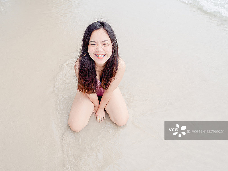 快乐的亚洲年轻女子在海滩上的肖像图片素材
