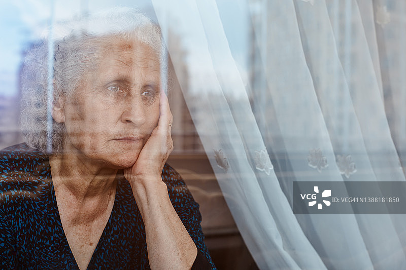 老女人独自坐着，望着窗外，陷入了深深的沉思和悲伤图片素材