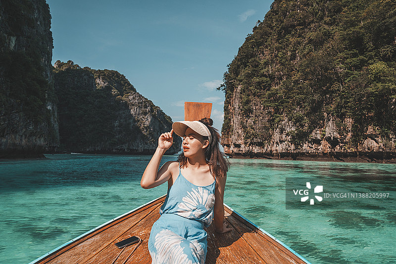 快乐的旅行者女人在夏天穿着欢乐的乐趣放松在船上，玛雅海滩，披皮岛，旅游普吉岛，甲米，旅游泰国，美丽的目的地亚洲，夏季假期户外度假旅行图片素材