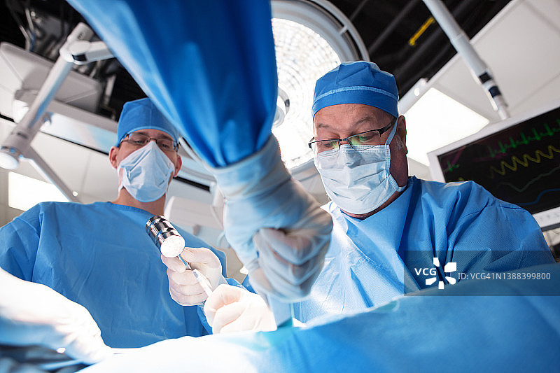 白人男性外科医生穿着手术服给病人做手术图片素材