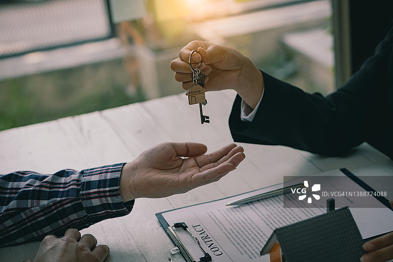 销售经理签署租约后将钥匙交给客户。关于提供住房抵押贷款和住房保险的房地产代理概念图片素材