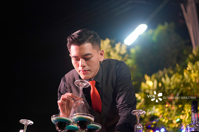 亚洲调酒师正在堆叠香槟塔，准备在晚会上调制烈焰鸡尾酒。图片素材