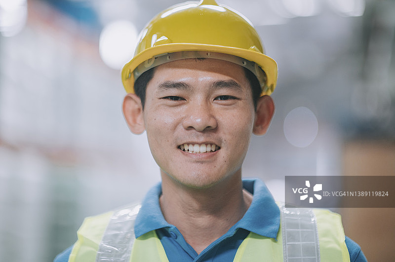 亚裔华裔男性仓库工人，穿着防护服，微笑着看着镜头图片素材