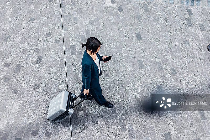 俯视图的女商人使用手机和步行与行李在停车场图片素材