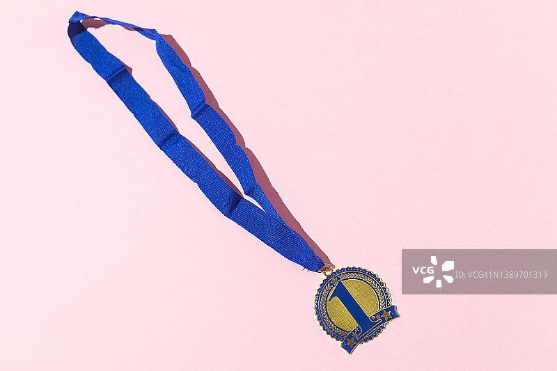 第一名冠军奖牌与数字1蓝色和蓝色带子在粉红色的背景。竞争的概念，优胜者，运动，胜利，冠军和第一名。图片素材