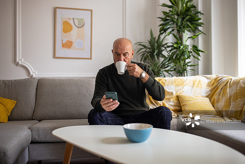 白人老人一边喝咖啡一边用手机图片素材
