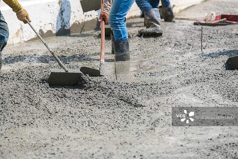 工人们帮助挖水泥，浇筑混凝土道路和完成工作图片素材