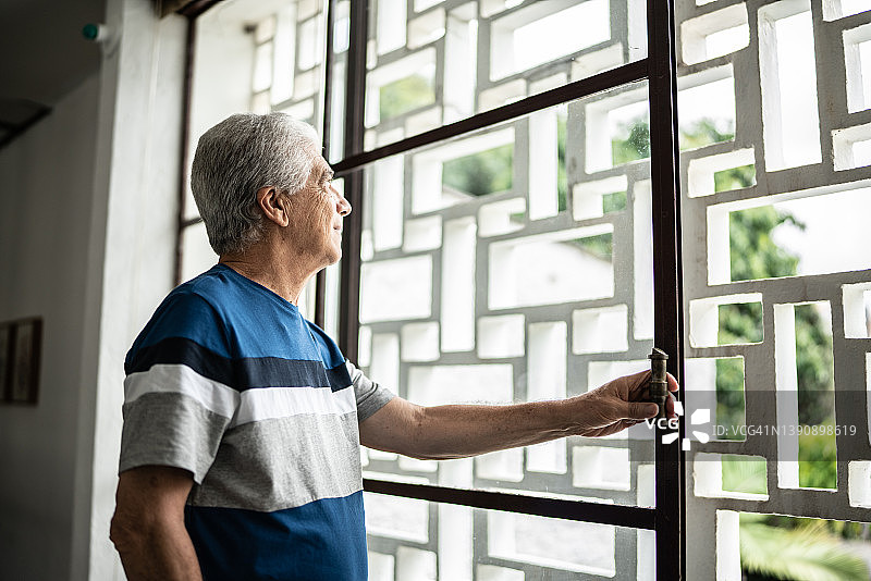 一位沉思的老人从家里的窗户往里看图片素材
