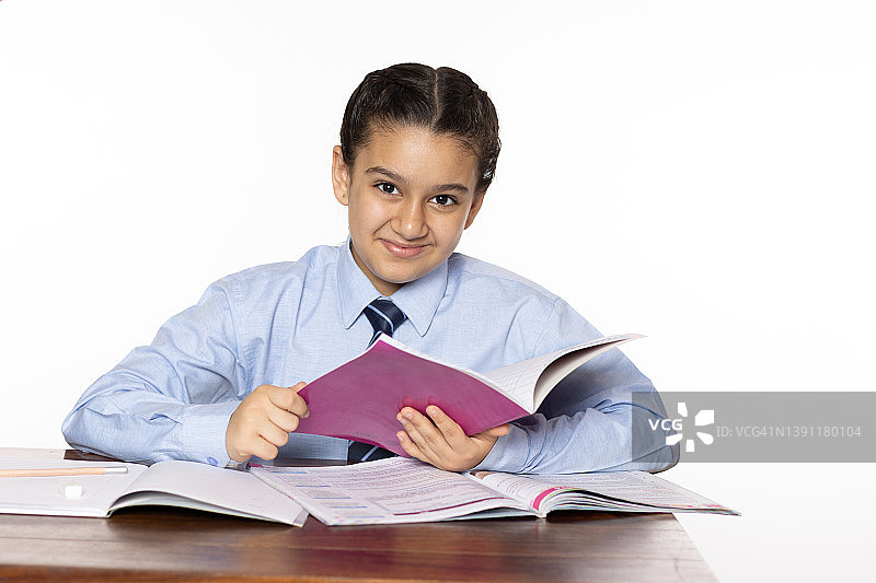 小学的小女孩坐在教室里拿着笔记本孤立在白色的背景图片素材
