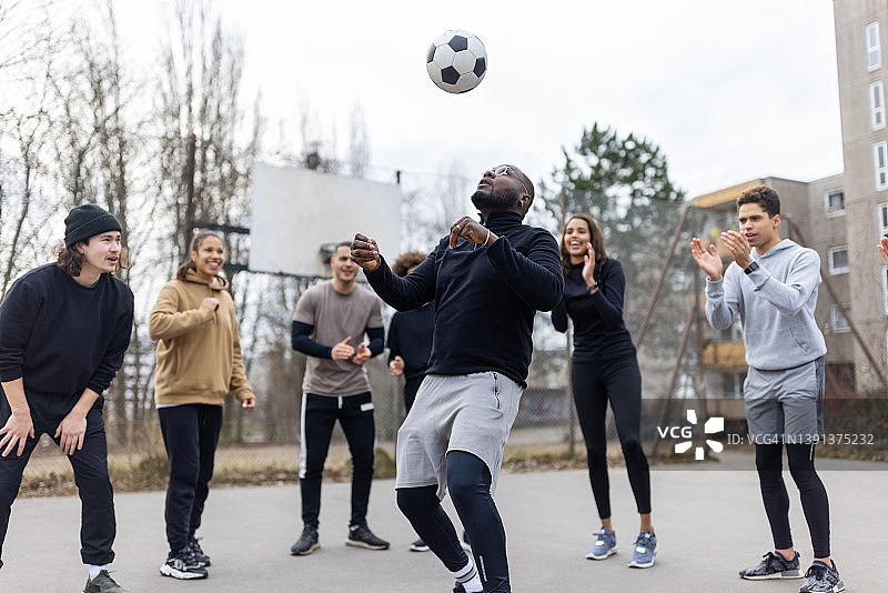 一名非洲男子在中间玩弄足球，朋友们围成一圈站着图片素材