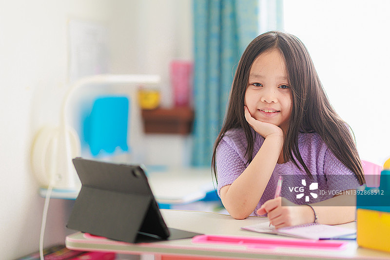 亚洲女孩在家用平板电脑做作业。教育科技理念。图片素材