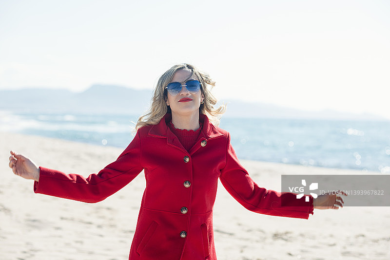 穿红色外套的女人在春天的海滩上玩图片素材