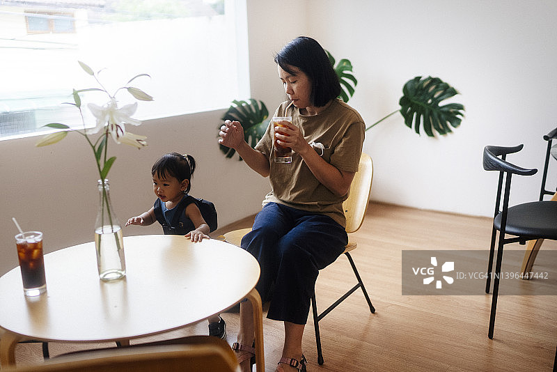 亚洲的年轻母亲喝着咖啡，与女儿周末活动休闲放松。图片素材