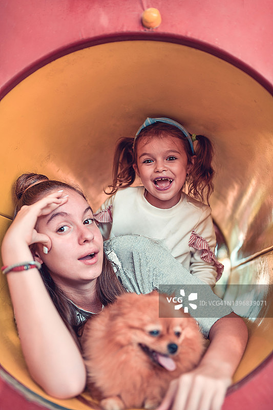 少女和她的孩子妹妹微笑着爬过操场管狗图片素材