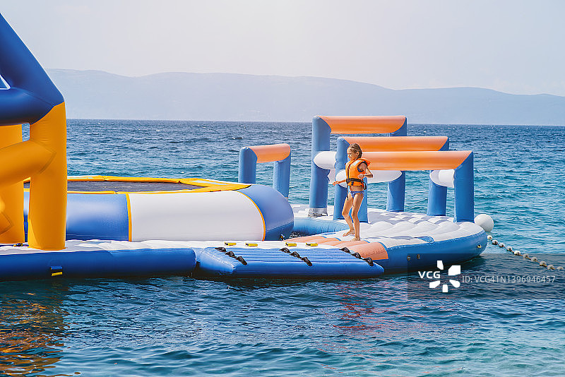 水上充气滑梯吸引游客。水上娱乐概念。假期或假日概念。充气水上公园。儿童在充气娱乐水上景点和海上滑梯。图片素材