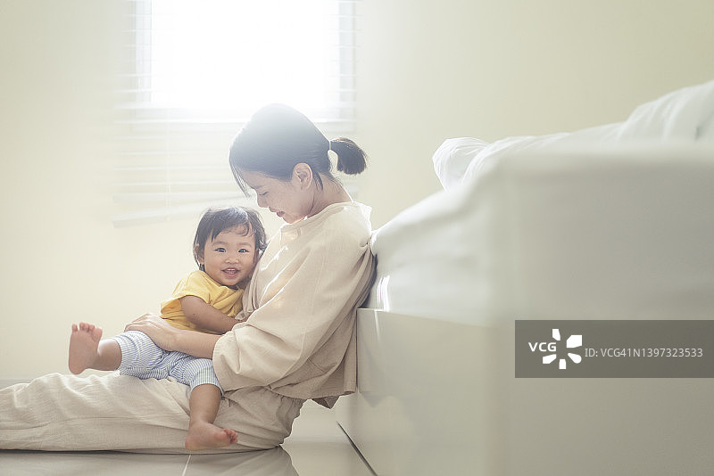 亚洲母亲积极的情感拥抱和哺育女儿，女儿抚摸母亲展现彼此的爱的家庭生活关系图片素材