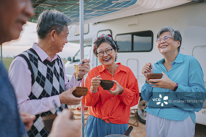 亚洲的中国老朋友们在稻田里的露营车旁享用晚餐图片素材