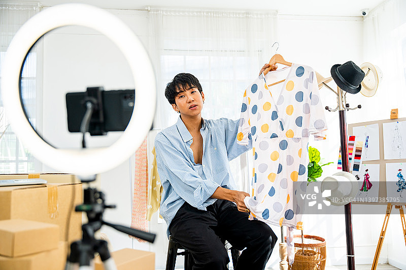 在家庭工作室工作的亚洲年轻时装设计师。一个在网上卖衣服的小企业主。图片素材