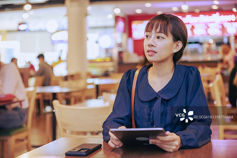 年轻的亚洲女商人在机场离境区工作或用数字平板电脑阅读电子邮件。商务旅行的概念。图片素材