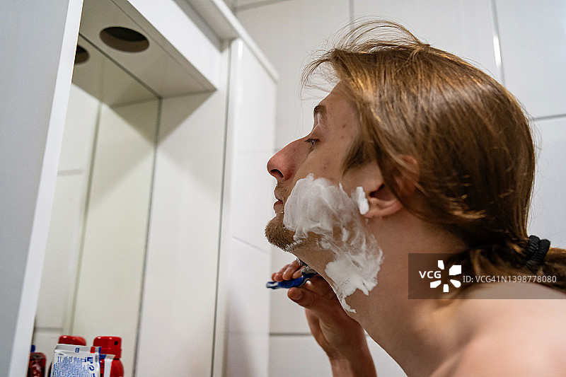 年轻男子在浴室刮胡子图片素材