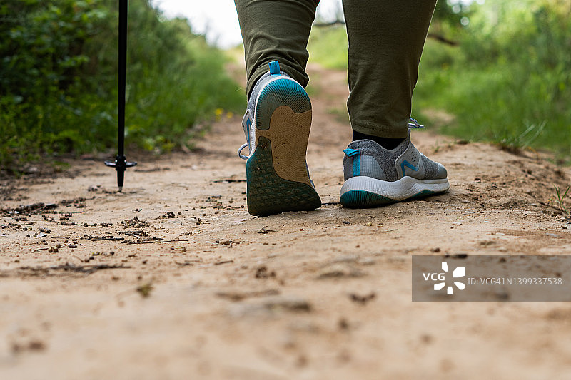 一个女人的脚在乡间小路上行走的后视图图片素材
