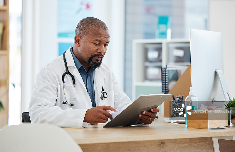 成年非洲裔美国医生检查病人的病历。专注的gp正在阅读剪贴板上的图表。严肃的医生在读病人报告。阅读医学文件的专业医师图片素材