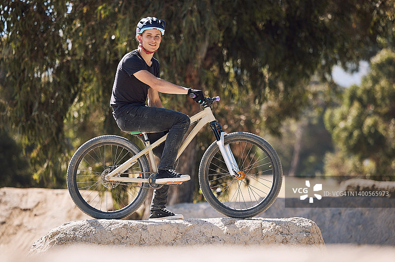一个戴着头盔的英俊男子的肖像，在外面骑自行车休息。男运动员在公园里锻炼。运动的男子在他的自行车上训练。保持心脏健康图片素材