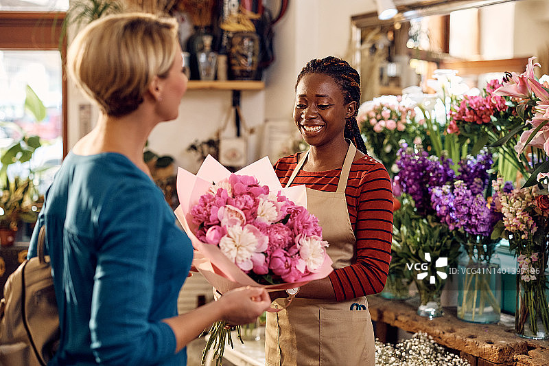 快乐的黑色花店给她的顾客花束花店。图片素材