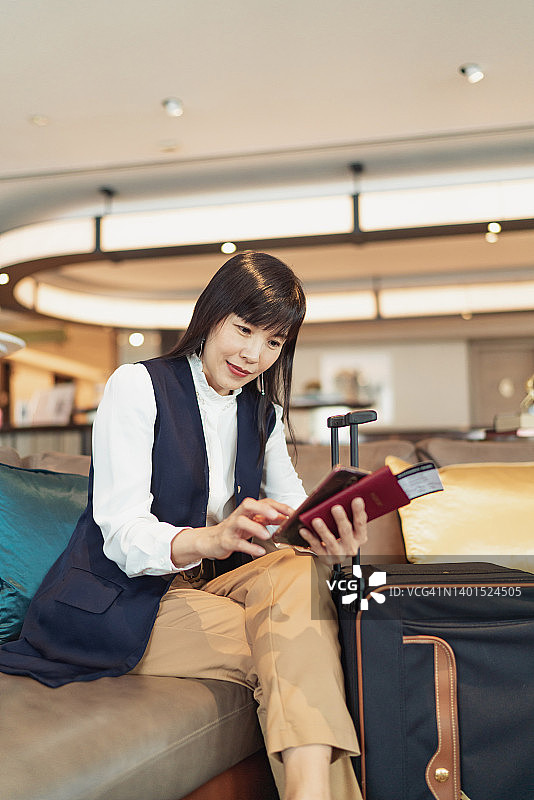 商务旅行——中国女商人在机场贵宾厅用手机查看她的航班信息图片素材
