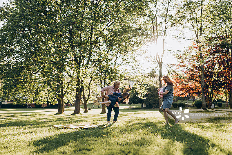 一个家庭里不同的几代人在阳光明媚的日子里一起在公园里度过。图片素材