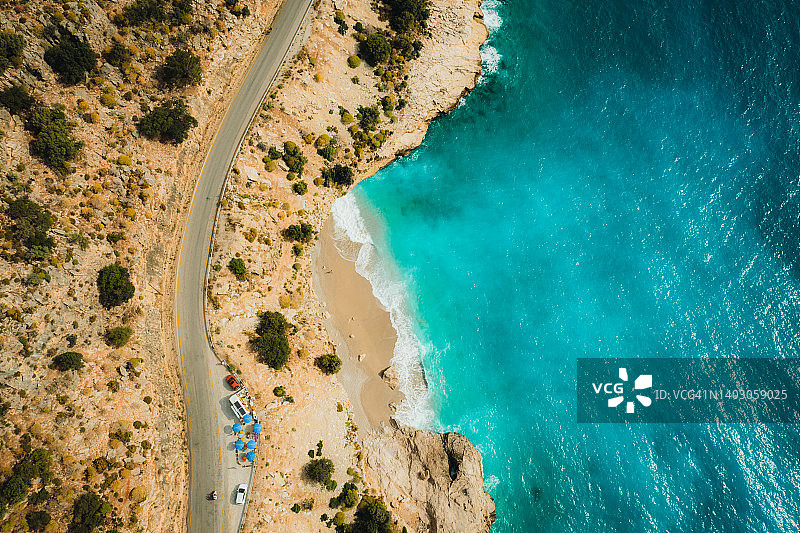 在土耳其的Oludeniz，沿着tuqueouise海滩和绿色山丘的山路行驶的汽车的风景鸟瞰图图片素材