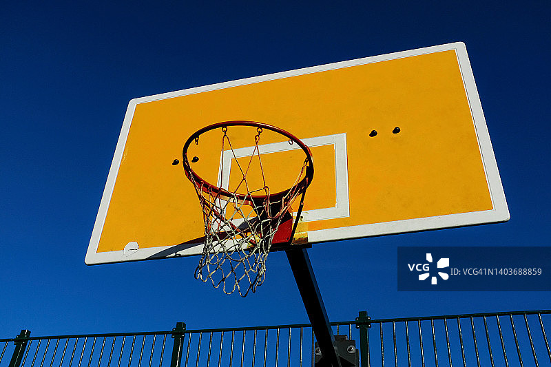 一个明亮的篮球盾牌，在蓝天的背景下，在一个开放的球场上。体育理念，实现目标。图片素材