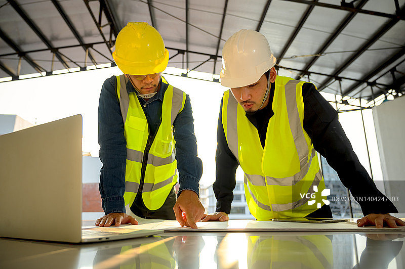 土木工程师和施工主管在施工现场检查建筑物的内部施工。建筑工程师或建筑师和工头检查建筑内部的施工。图片素材