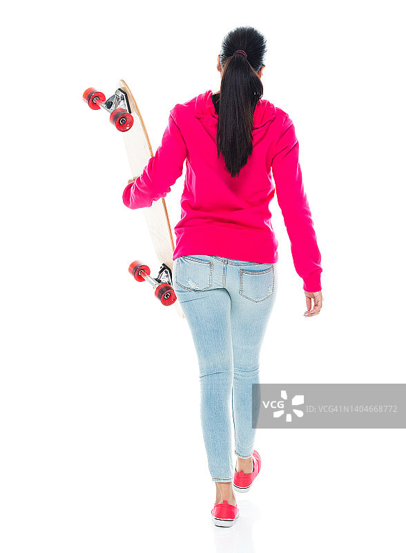 z一代女性在白色背景下玩滑板，穿着运动衫图片素材
