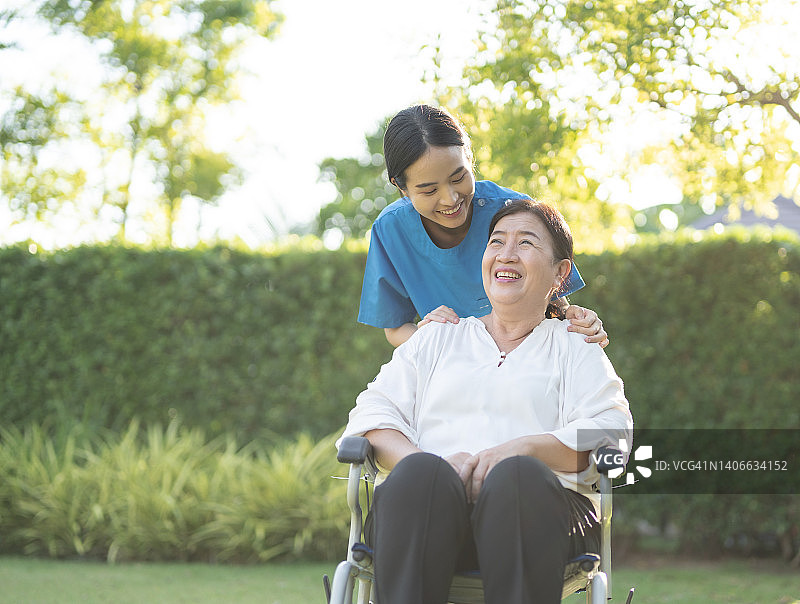 亚洲女护士在家协助轮椅上的女老年病人的幸福情绪图片素材