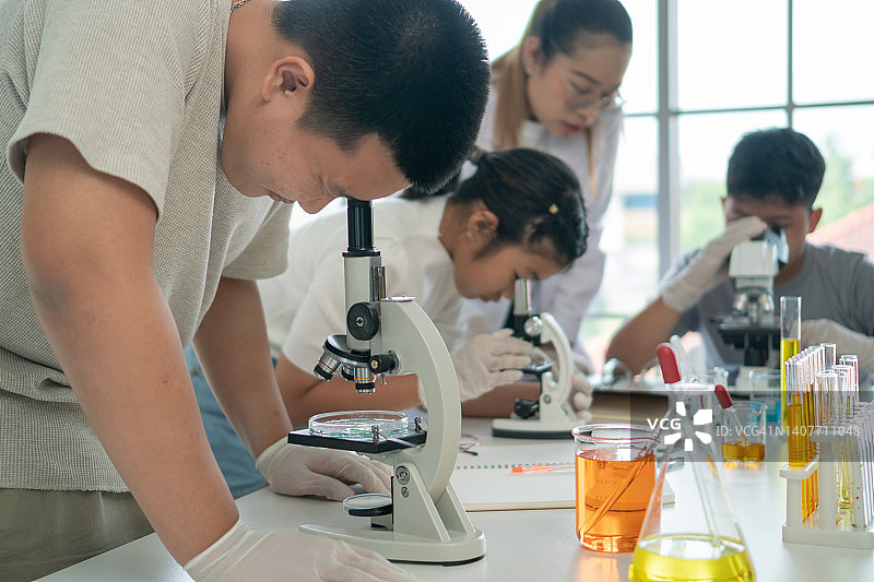学生们正在愉快地使用显微镜学习科学科目。图片素材