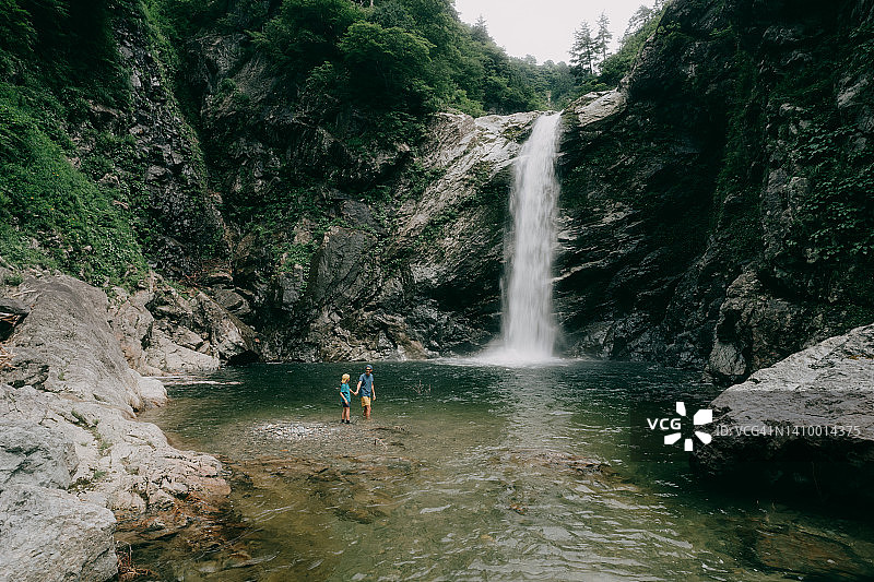 父亲和孩子在瀑布前图片素材